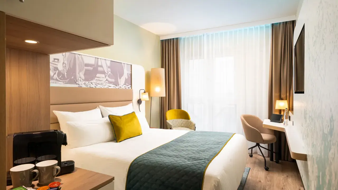 Modern Hotelzimmer mit Bett, Schreibtisch und Kaffeemaschine.