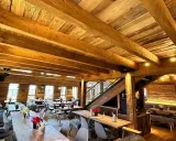 Gemütliches Holzinterieur eines Restaurants mit Holzbalken und Tischen.