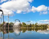 Aussicht auf Achterbahnen und einen Freizeitpark mit Spiegelung im Wasser.