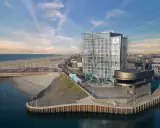 Modernes Hotel am Meer mit Glasfassade, Strand und Hafen.