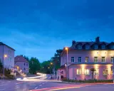 Parkhotel Güldene Berge in Harz bei Nacht, mit Lichtern und Spuren von Autos.
