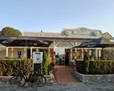 Zwei Fahrräder vor dem Restaurant "Alt Borkum" mit Sonnenschirmen und Büschen.
