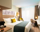 Modern Hotelzimmer mit Bett, Schreibtisch und Kaffeemaschine.