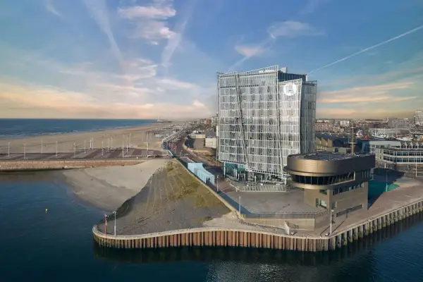 Modernes Hotel am Meer mit Glasfassade, Strand und Hafen.