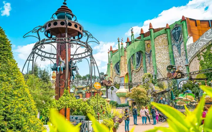 Phantasialand: Kettenkarussell und grüne Fantasiegebäude mit Achterbahn.